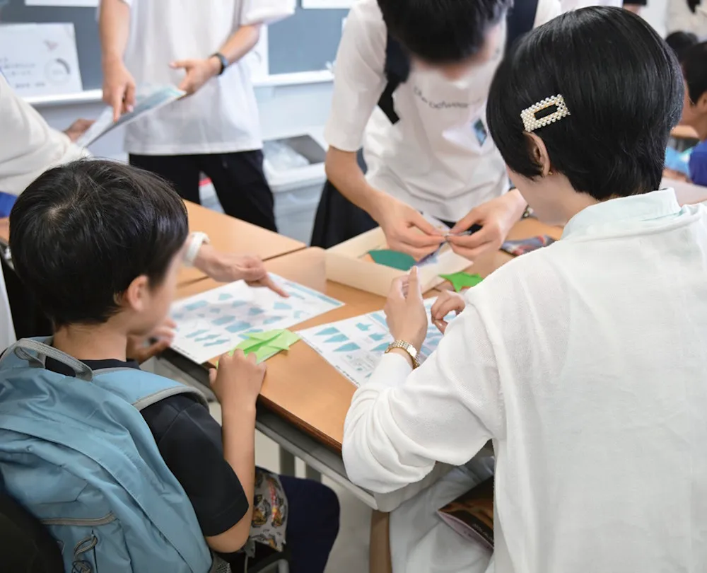 部員の指導の下小学生が折り紙を制作する様子