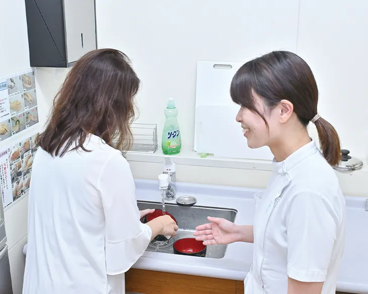 キッチンを想定した設備で、食器洗いの動作を指導しているようす